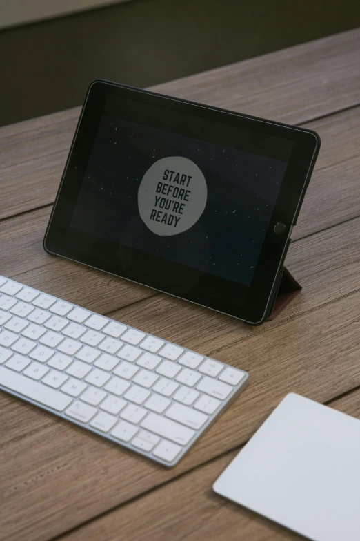 tablet on top of a wooden table next to keyboard and mouse