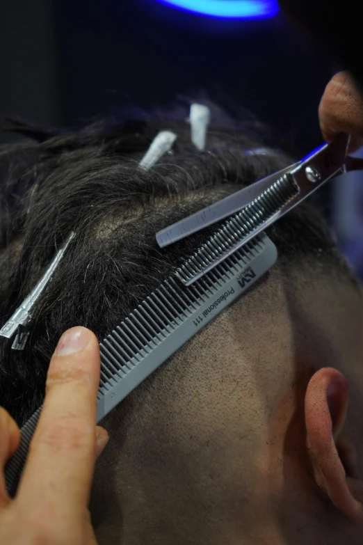 a man having his hair cut with scissors