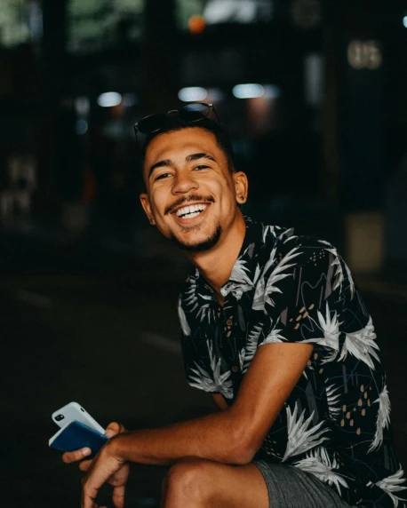 a man sitting outside with his cell phone smiling