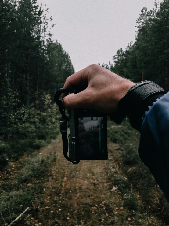 a person holds a camera up over an abandoned dirt path