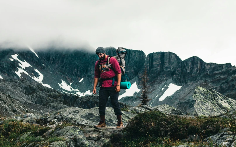 two people standing on some large rocks in the mountains