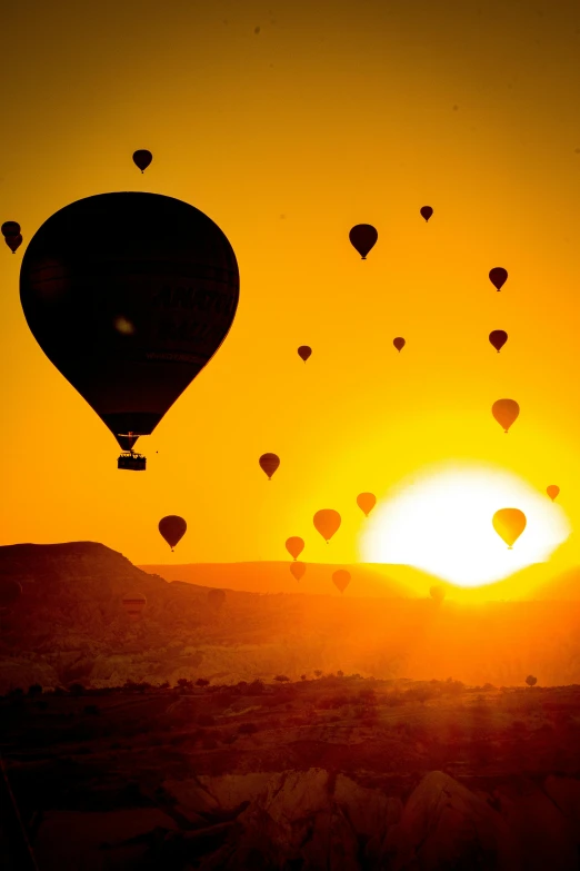 a very bright and yellow sunset with many balloons in the sky