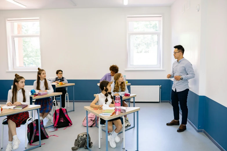 a man is standing in front of a class room with many children