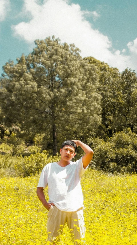 a man standing in a field with his hand up to his head