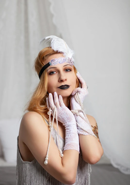 a young lady wearing white gloves and an extravagant hat is posing