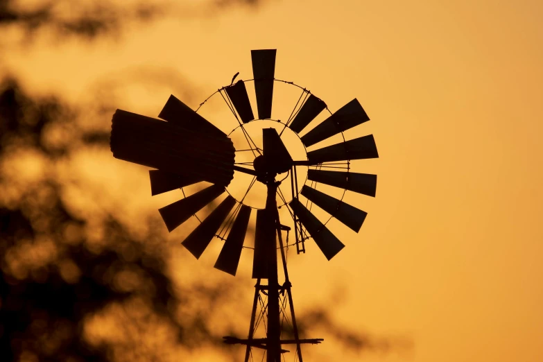 a windmill in silhouette with a gold sky