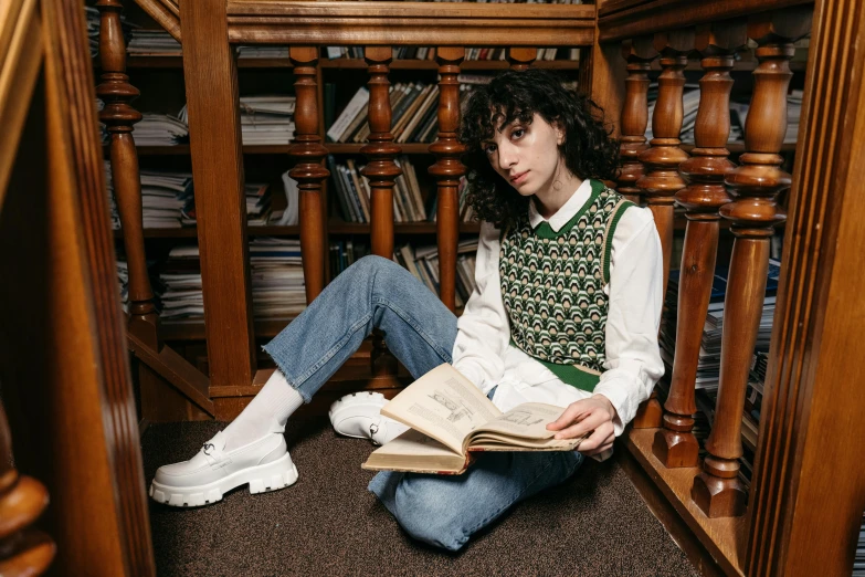 a girl sitting in front of a bookcase reading a book