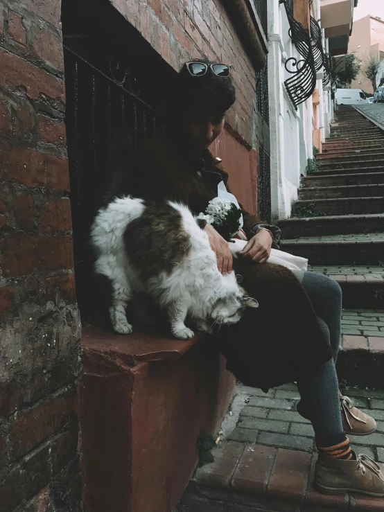 a woman sitting on the stairs petting her dog