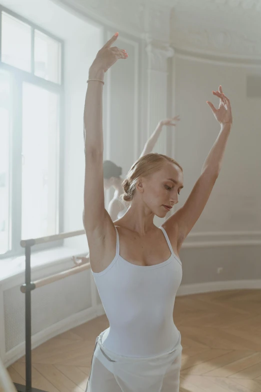 a woman in white clothing stands on one leg