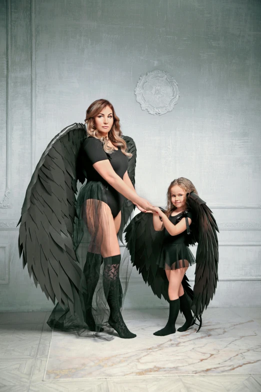 woman in black outfit posing with little girl dressed up as angel