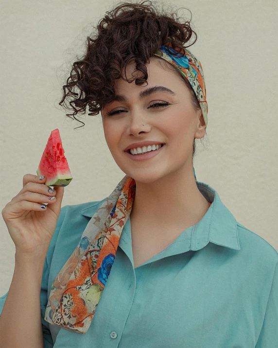 a young woman holding a piece of watermelon and smiling