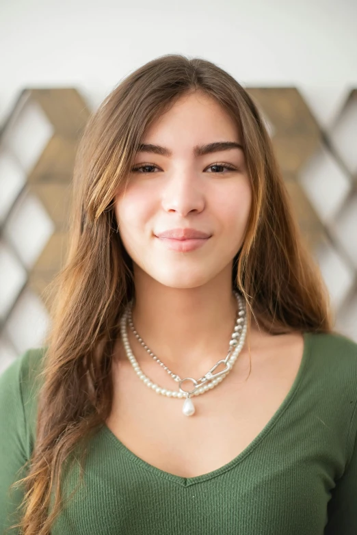 an attractive woman wearing a green top with beads and pearls