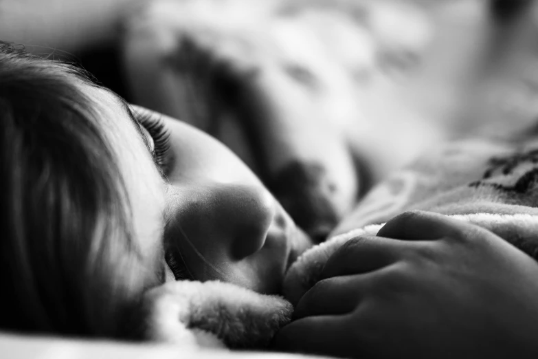 a girl laying down in bed with her face covered by a stuffed animal