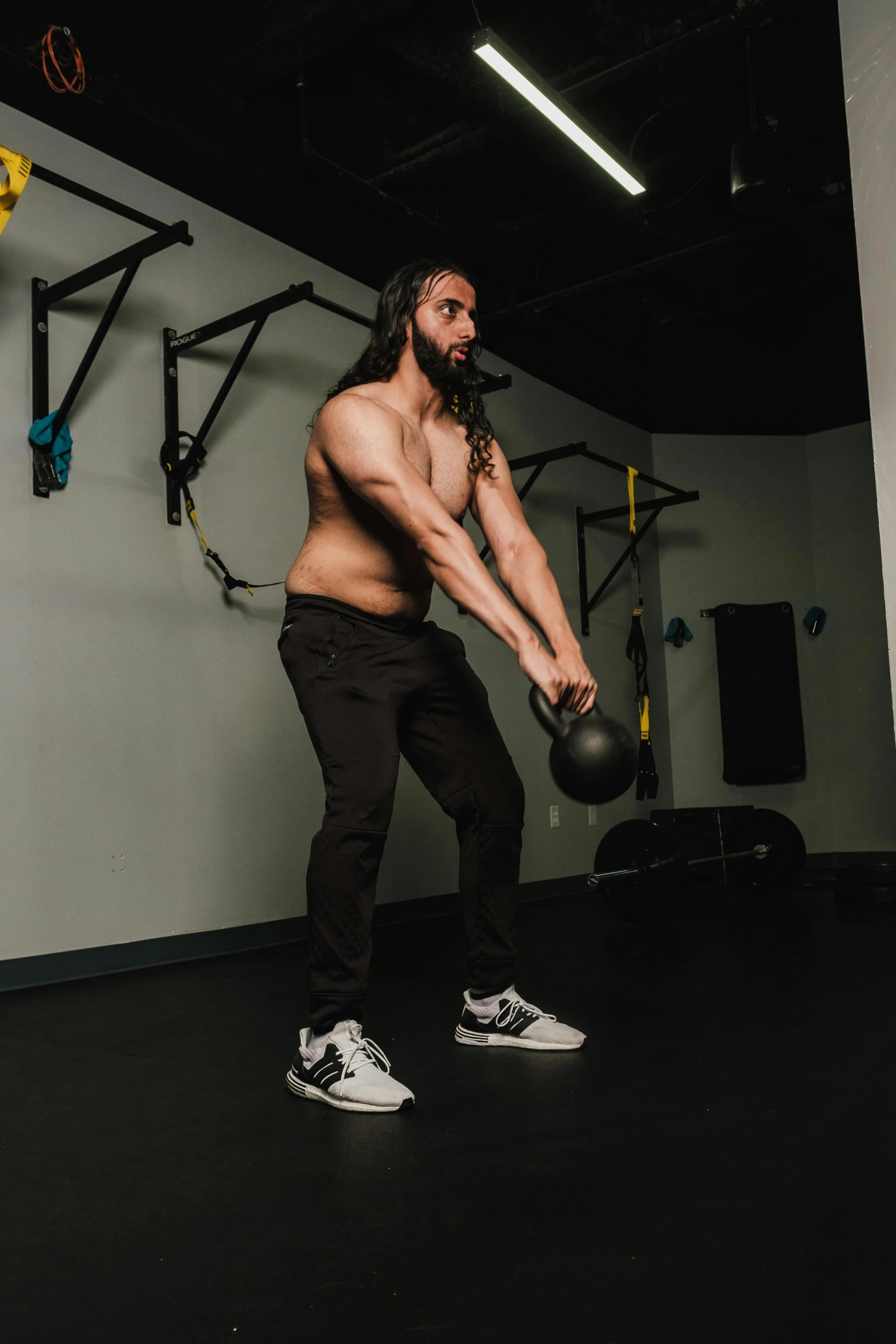 a shirtless man is holding a gym ball while he swings a medicine