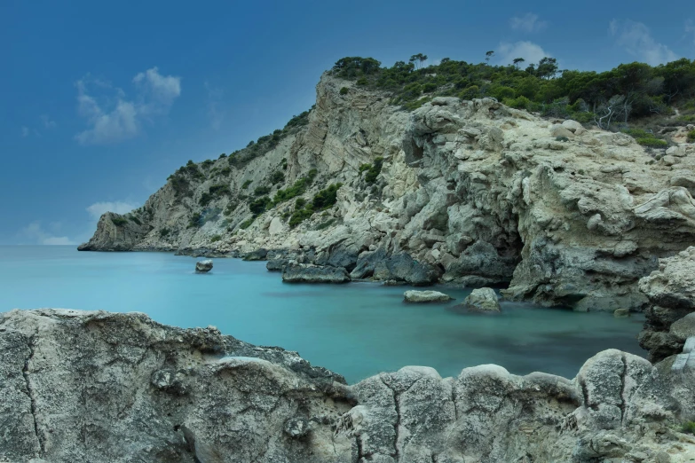 a lake with some blue water next to a rocky hillside