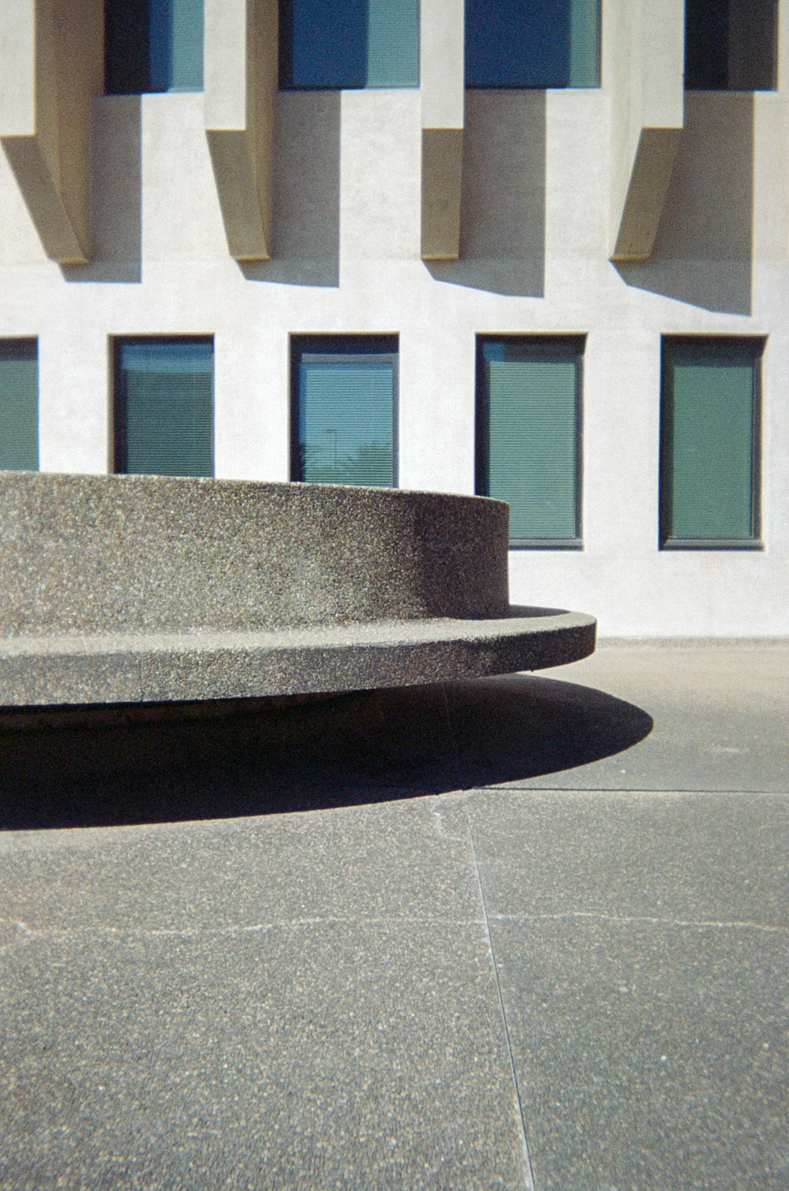 a cement park bench with several windows and a concrete floor