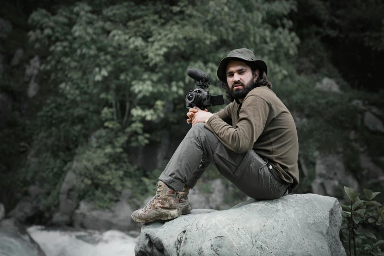 the man is sitting on top of a rock holding a camera