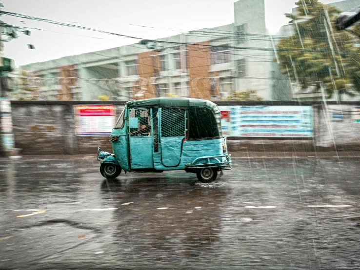 a small vehicle drives down the road in the rain