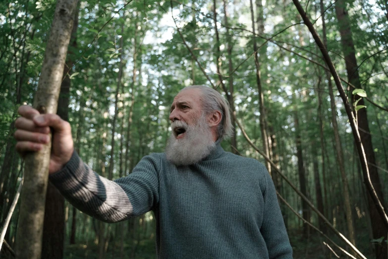 man in the woods holding onto a tree nch