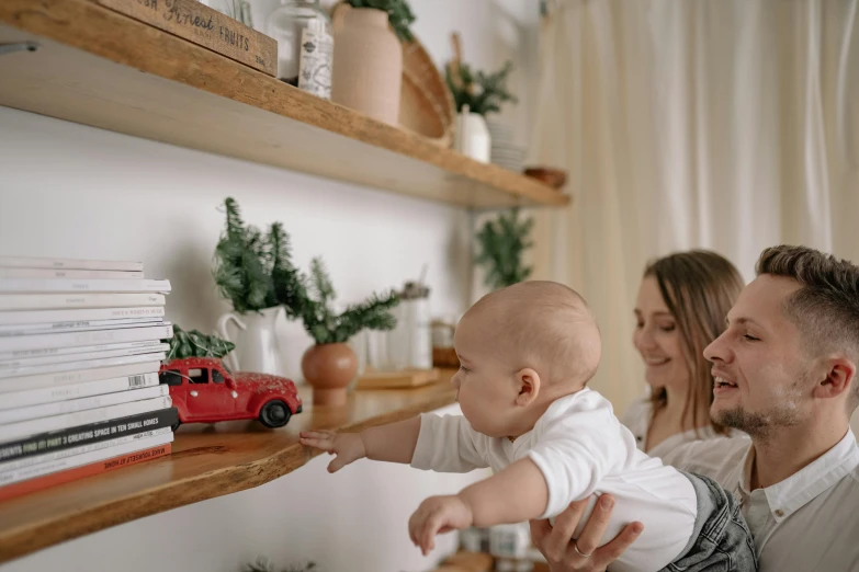 a woman is holding a baby while he holds a toy truck