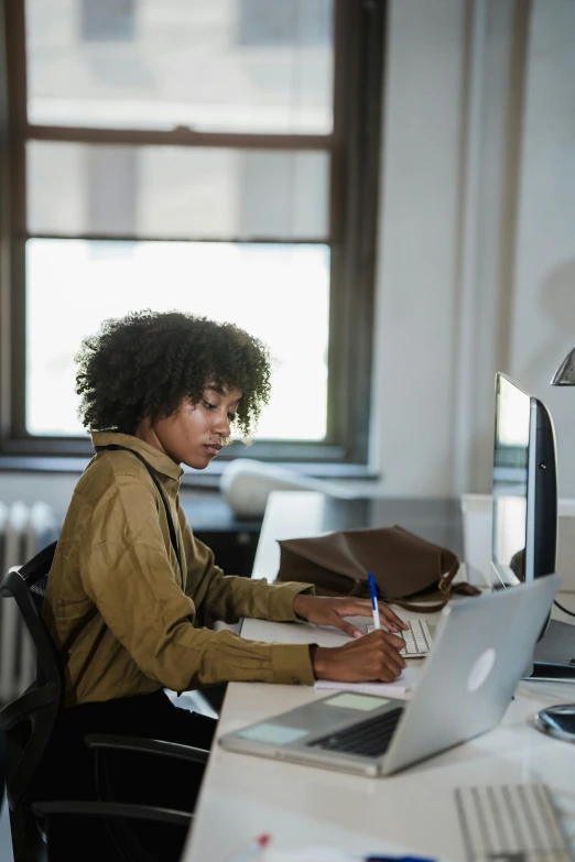 an african american woman writes in her office desk