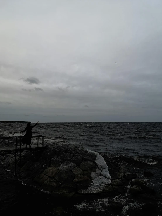 a person standing on a cliff next to the ocean