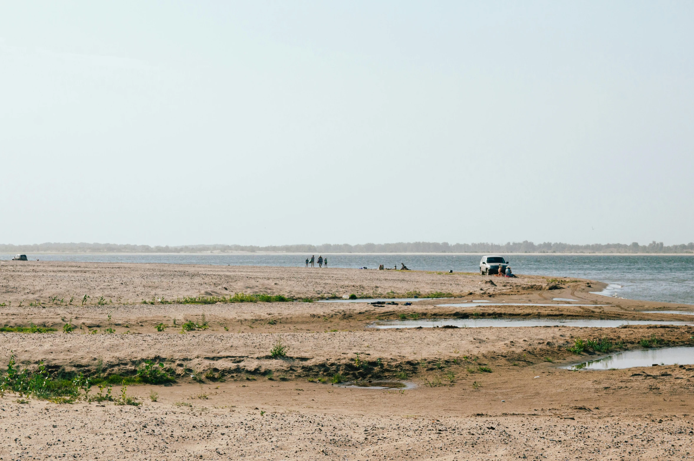 an empty beach with people walking in the sand