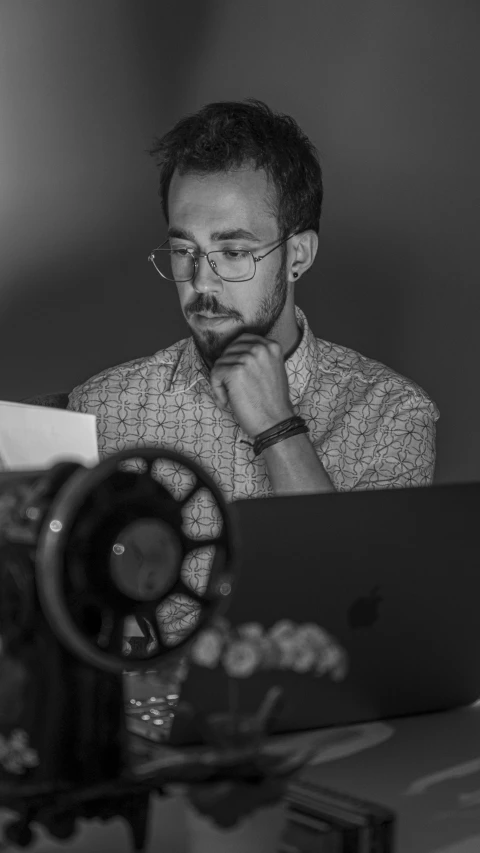 man looking at laptop screen from desk in dark room