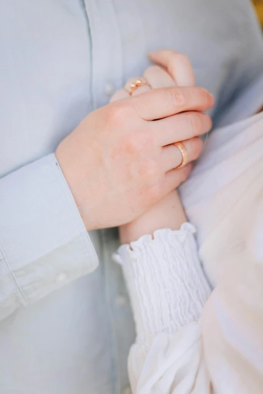 the two hands of a person holding onto an engagement ring