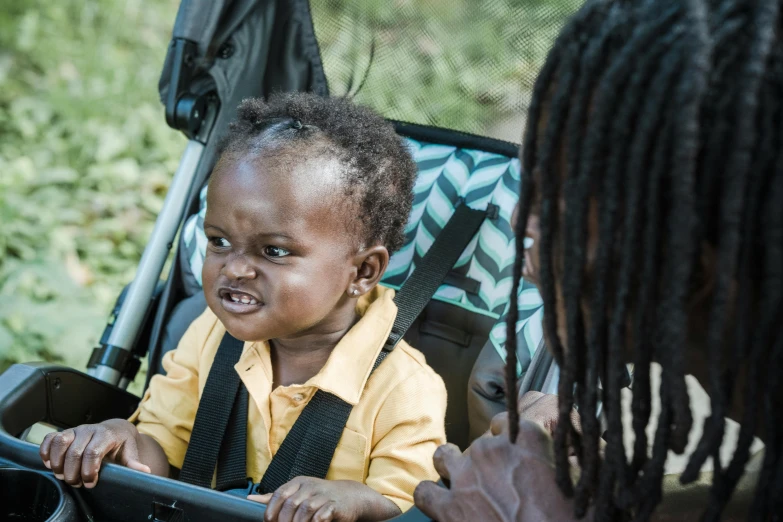 an african american girl is looking at a baby sitting in a stroller