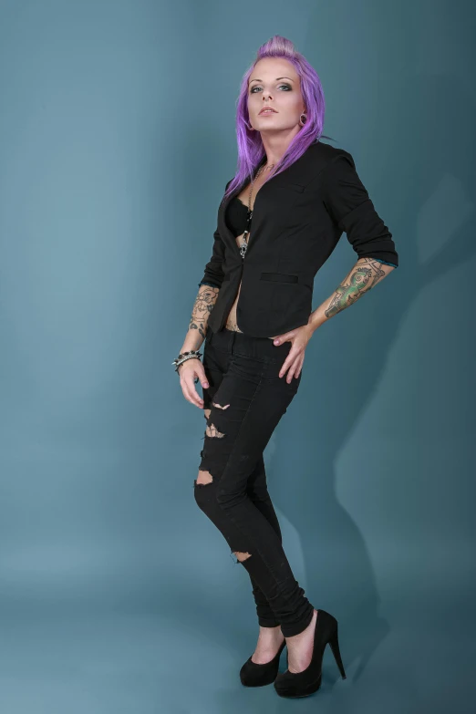 a woman with purple hair and tattoos standing on blue background