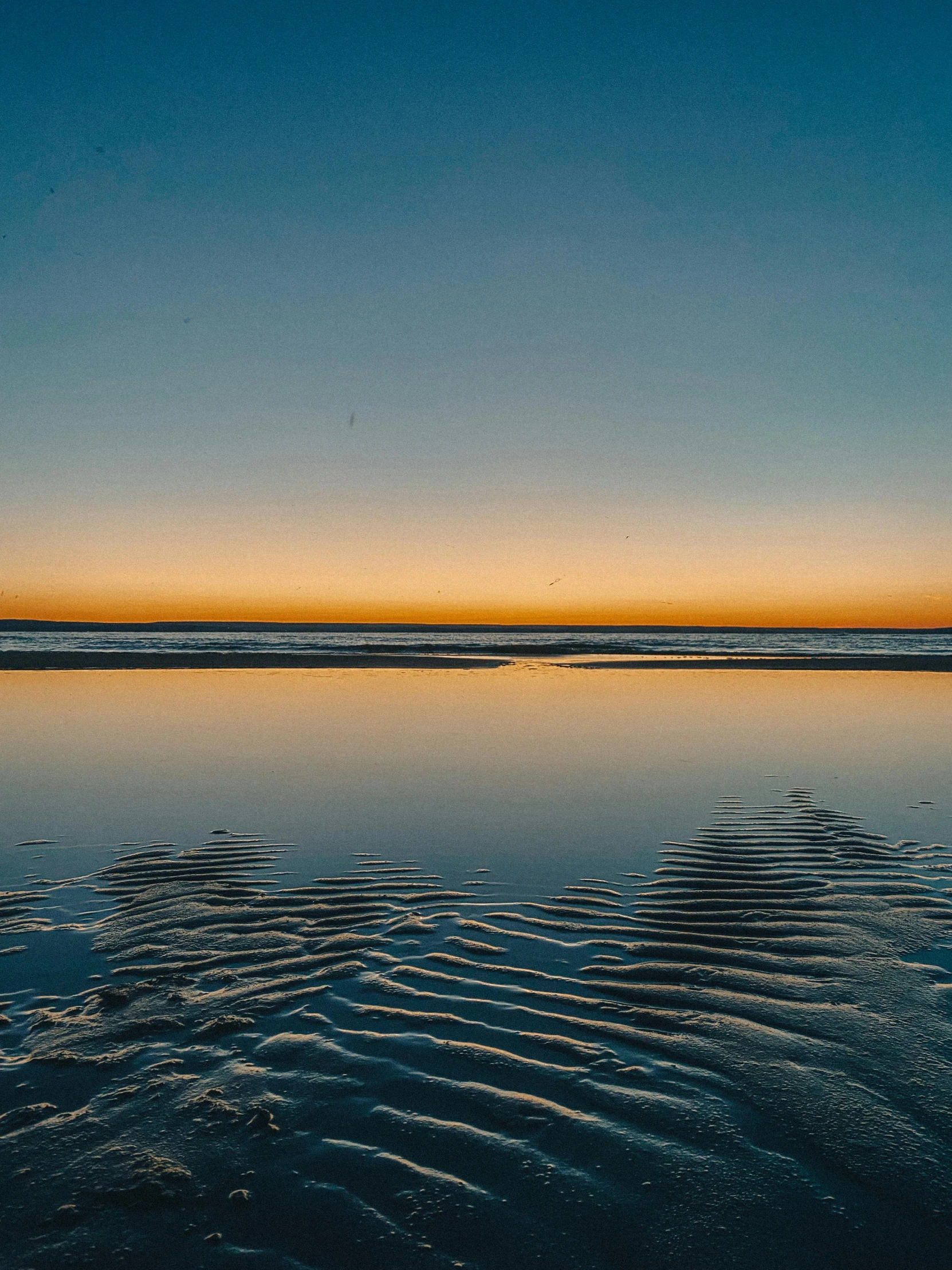 a beautiful sunset over the ocean with some small wave tracks