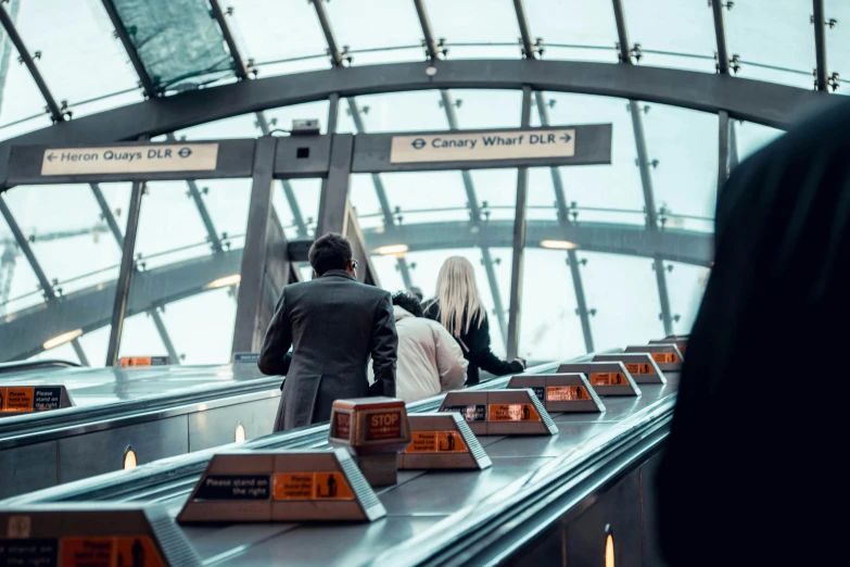 three people ride an escalator in a mall