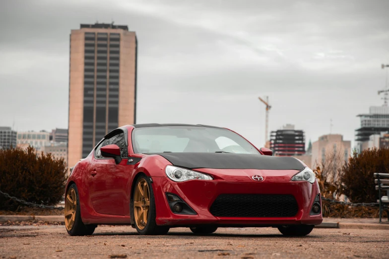 a red sci turbo sits on the ground in front of city skyline