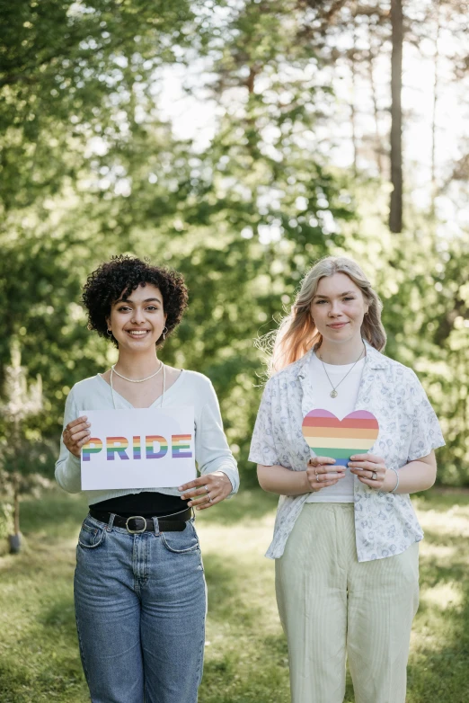 two women standing side by side holding signs in their hands