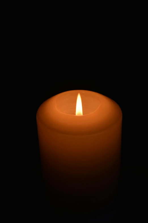 a lit candle on a black background with no light