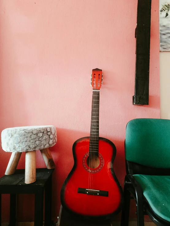 a red guitar sits on top of a stool