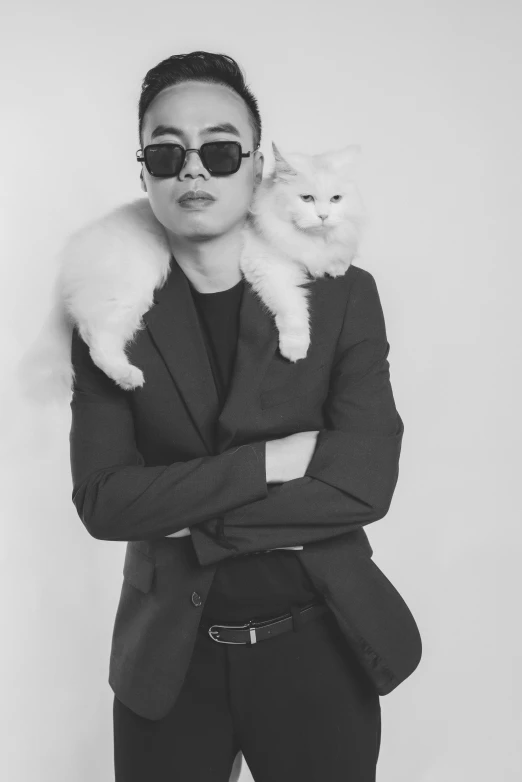 man wearing sunglasses holding up a cat on his shoulders