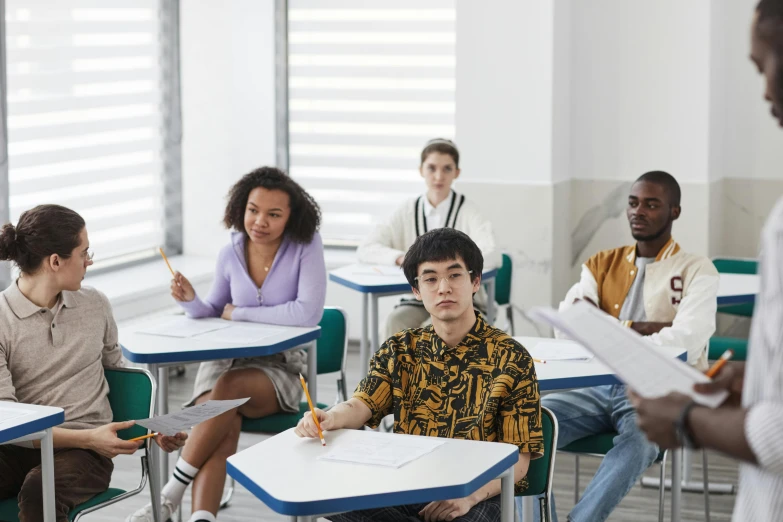 people are sitting around desks in a classroom