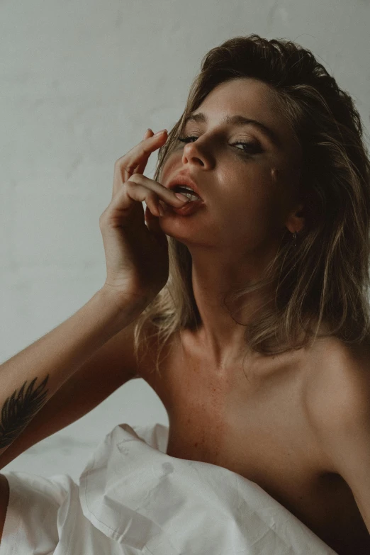 a woman laying on top of a bed covered in white sheets