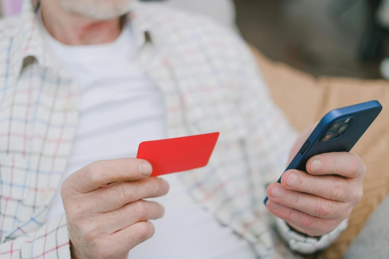 an elderly man looking at his smartphone with an empty credit card