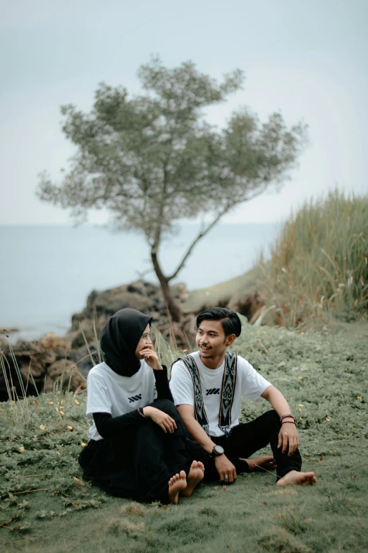 two people sitting on the ground together in grass