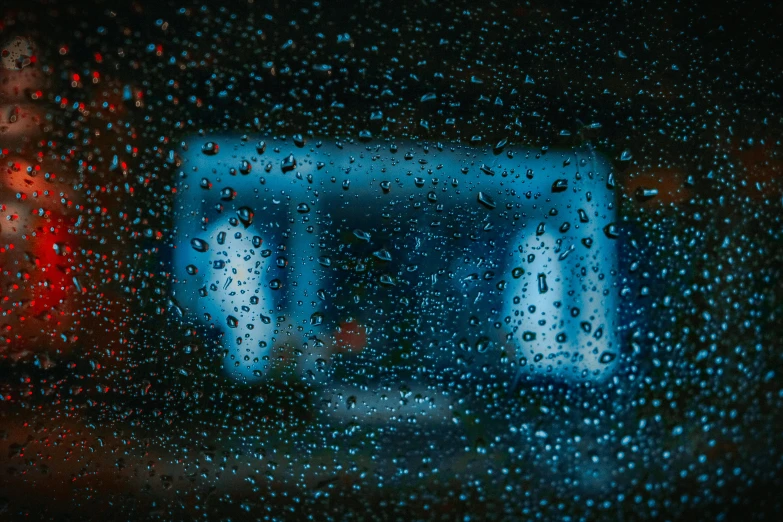 a wet glass window with a building in the rain