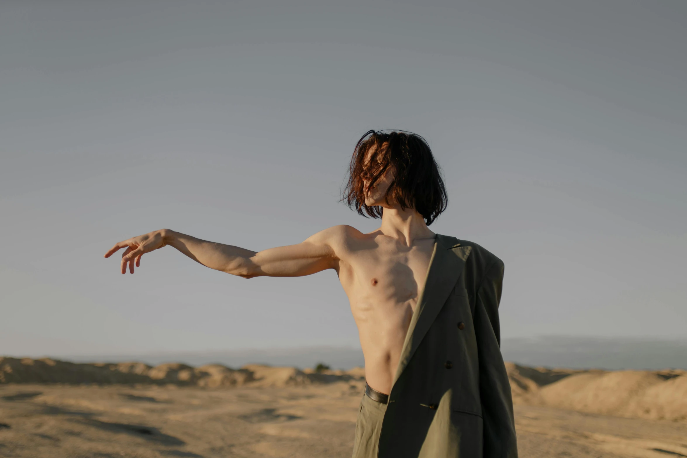 man standing in the desert holding his arm out towards soing