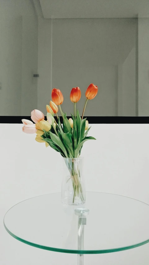 flowers are in a vase sitting on a glass table