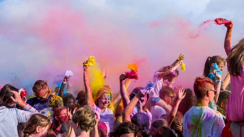 a crowd of people in colorful attire are throwing colored powder at each other