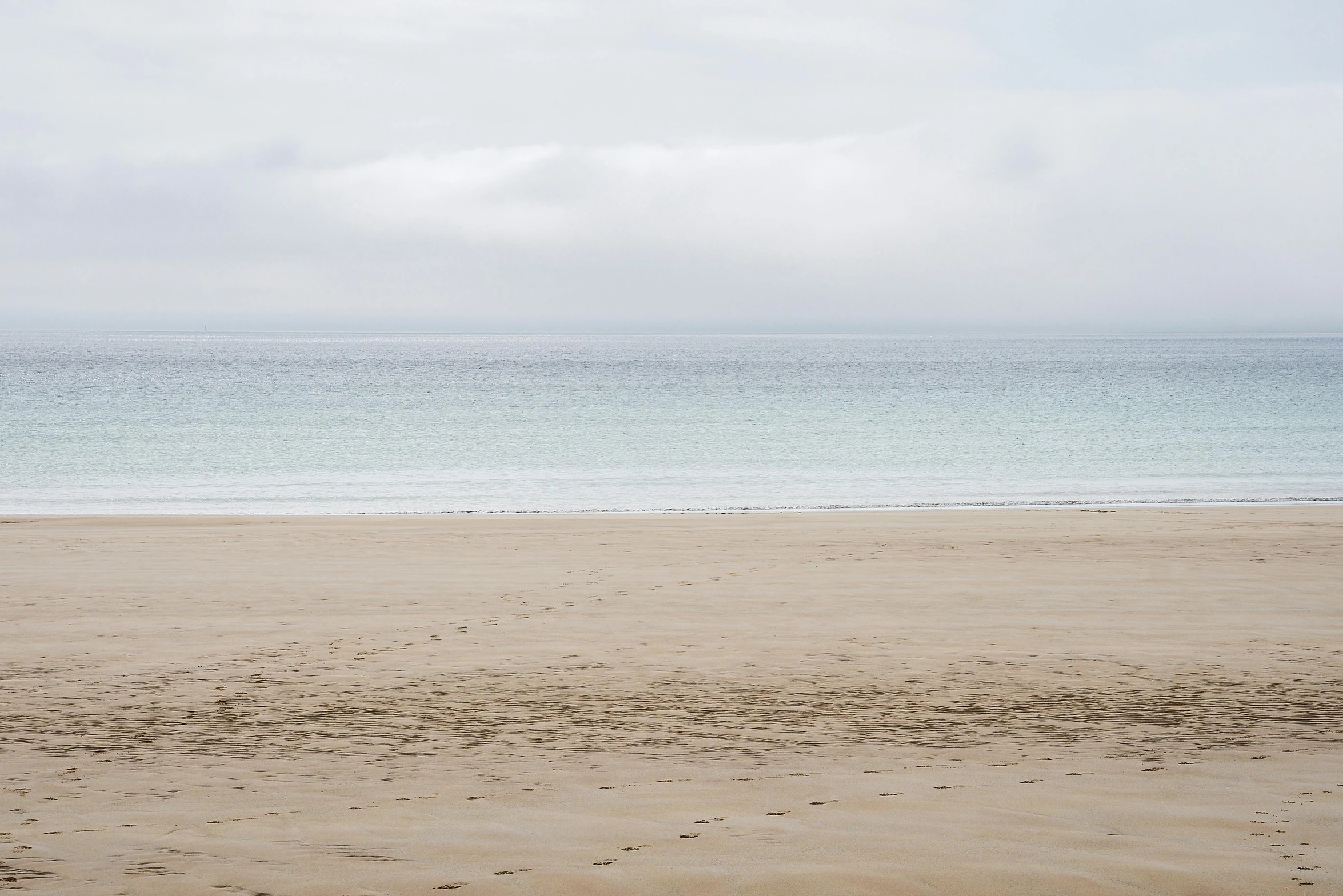 the view of an ocean and land beyond from a beach