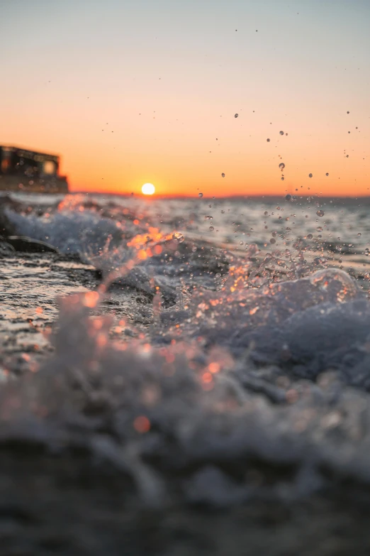 a sunset is seen over some waves on the ocean