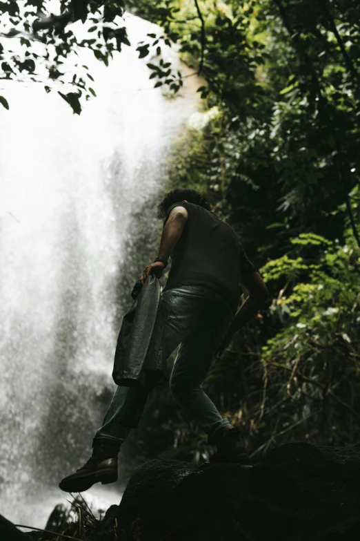 a man standing in front of a waterfall with a water jug