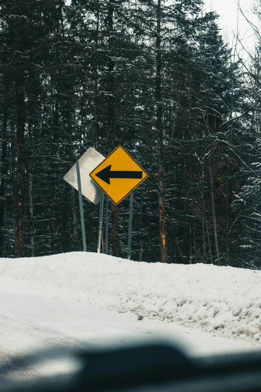 there is a snow covered field with a yellow and white street sign